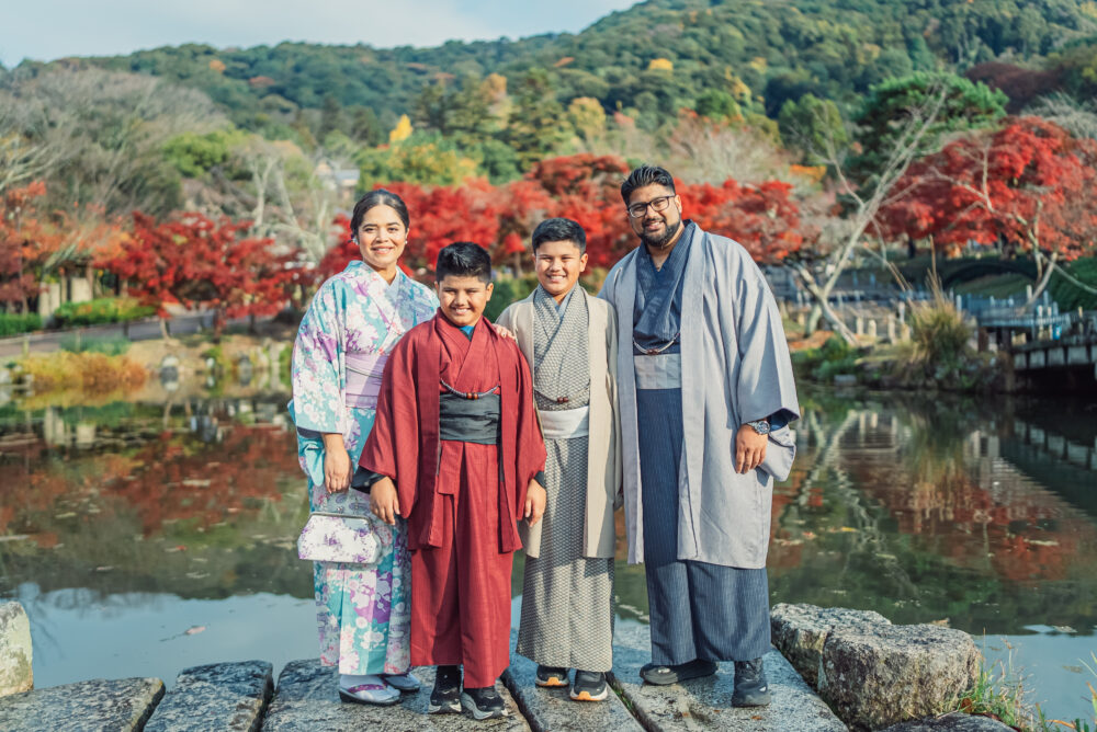 A family smiling together in front of the pond at Maruyama Park during a Kyoto family photoshoot