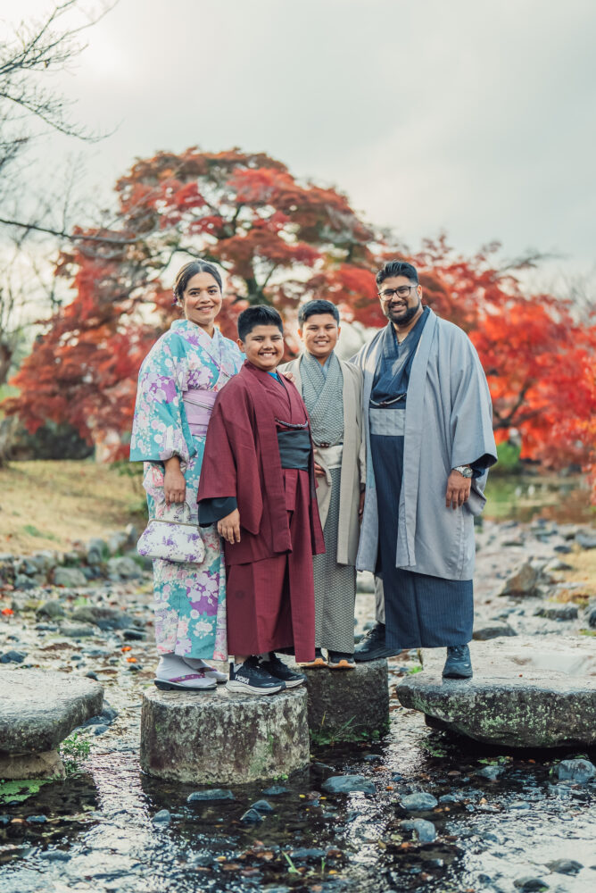 A family standing together on stepping stones surrounded by beautiful nature at Maruyama Park during a Kyoto family photoshoot
