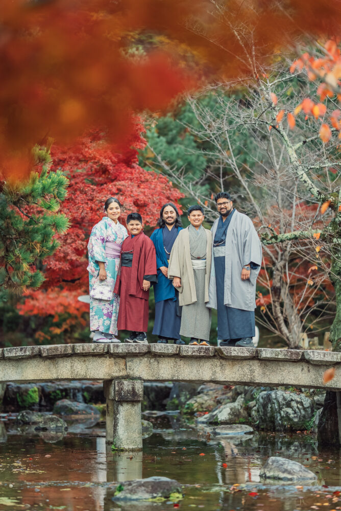 A family standing on a bridge over a stream during a natural family photoshoot at Maruyama Park Kyoto