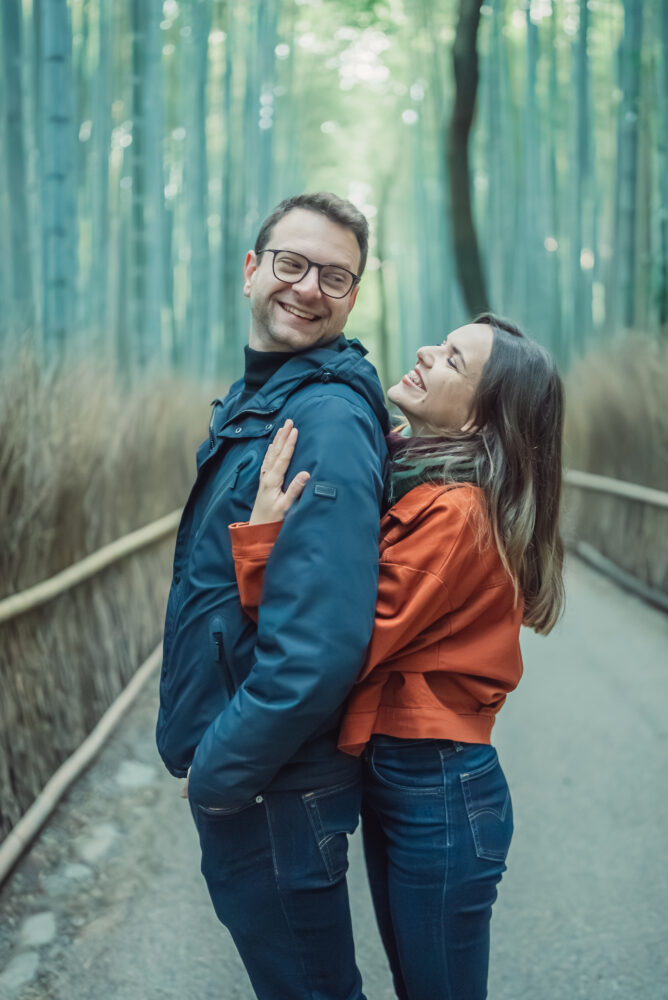 Engaged couple standing together in front of the famous Arashiyama Bamboo Forest during an early morning photoshoot in Kyoto