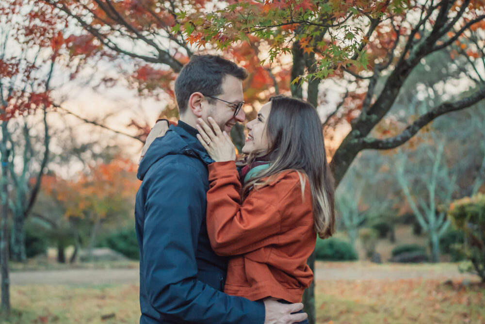Romantic engaged couple surrounded by colorful autumn foliage in Arashiyama Kyoto
