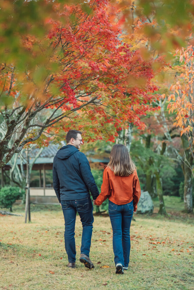 Engaged couple standing together surrounded by beautiful autumn leaves during a romantic photoshoot in Kyoto