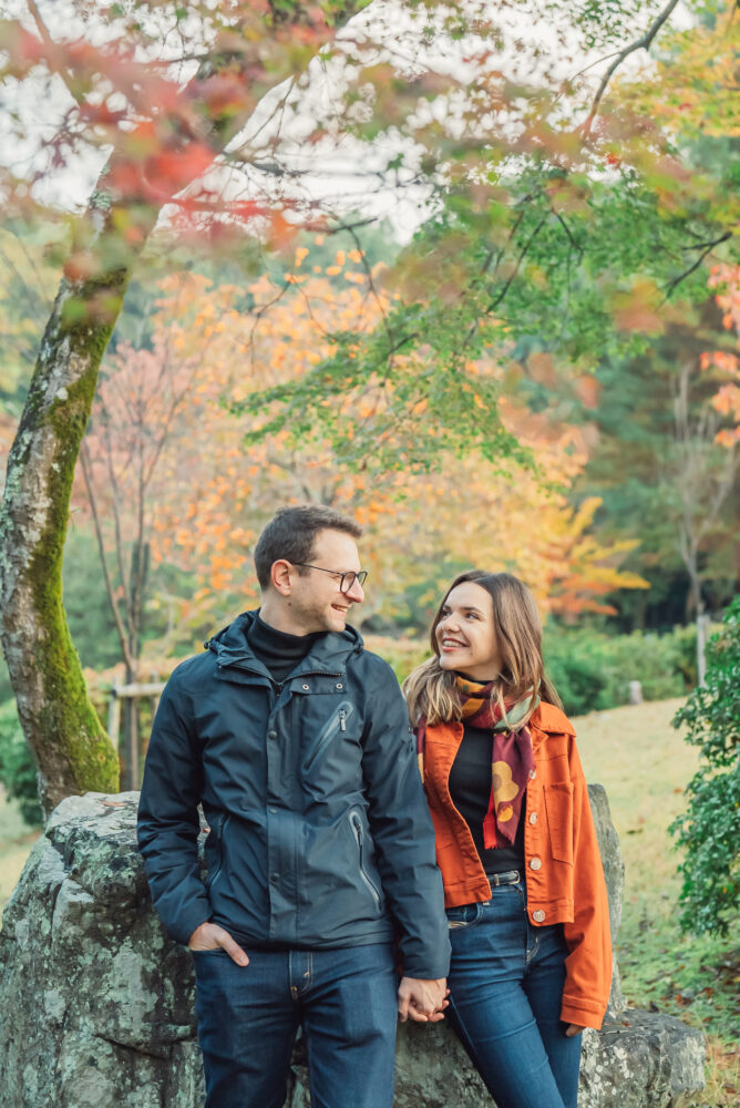 Engaged couple enjoying beautiful red and orange autumn leaves during a Kyoto engagement photoshoot