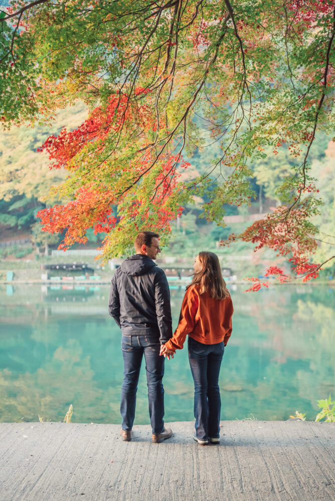 Natural portrait of an engaged couple surrounded by vibrant autumn foliage in Kyoto Japan
