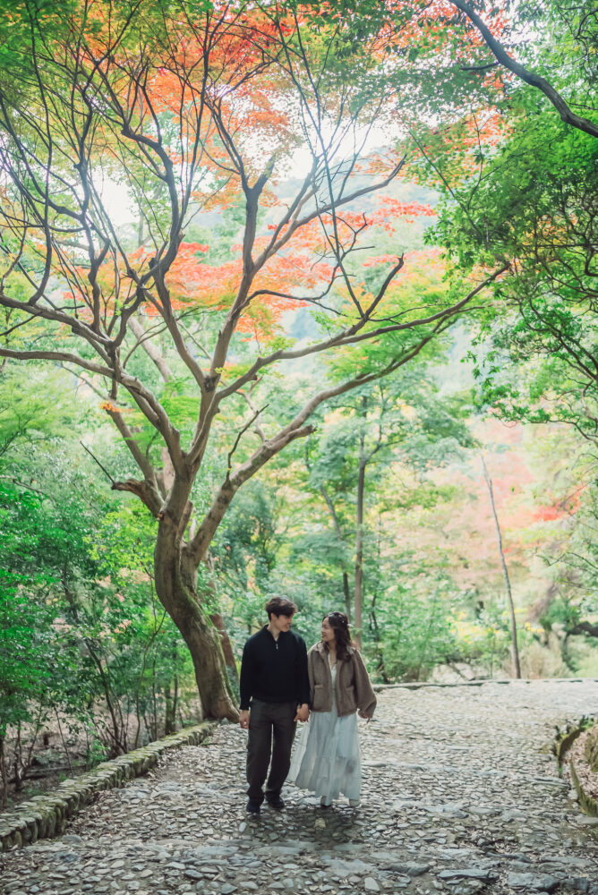 Engaged couple surrounded by beautiful autumn leaves in Arashiyama Kyoto during a romantic engagement photoshoot
