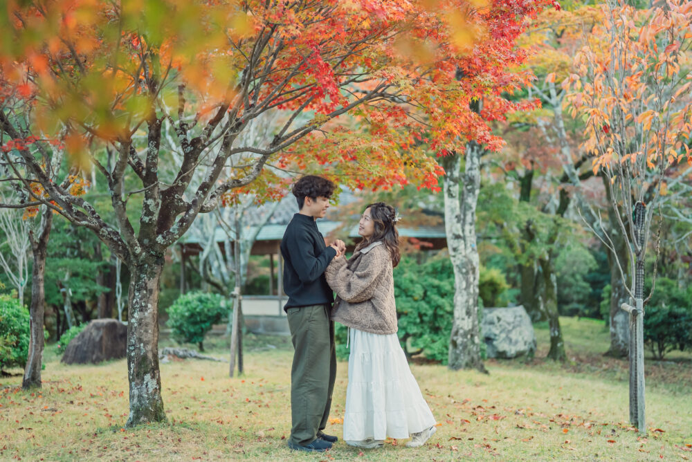 Engaged couple posing in front of the colorful autumn landscape of Arashiyama Kyoto