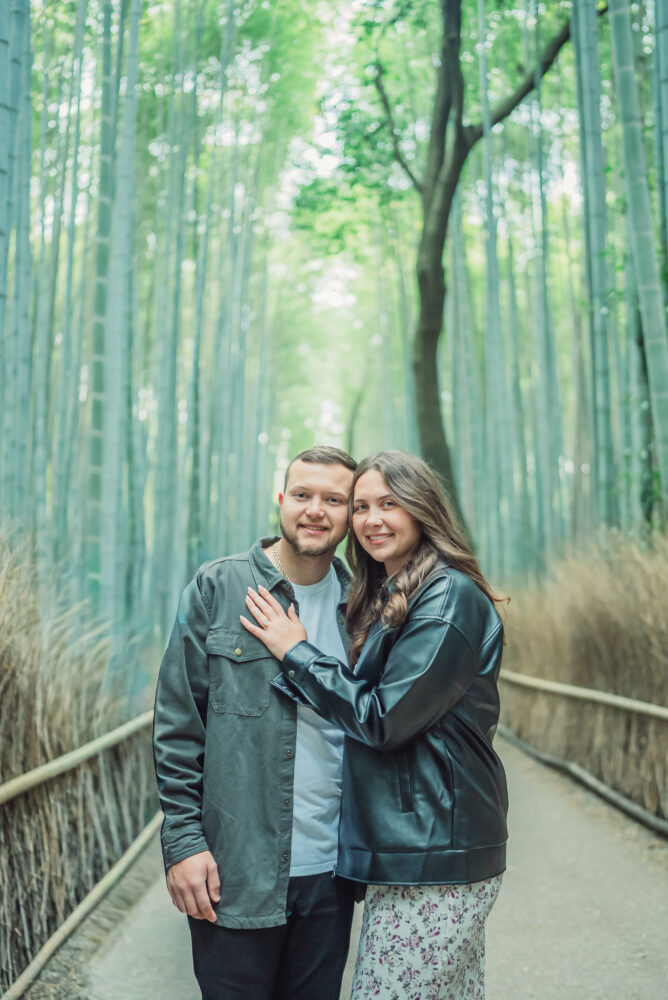 A romantic couple standing together in the peaceful bamboo forest of Arashiyama Kyoto surrounded by tall bamboo trees