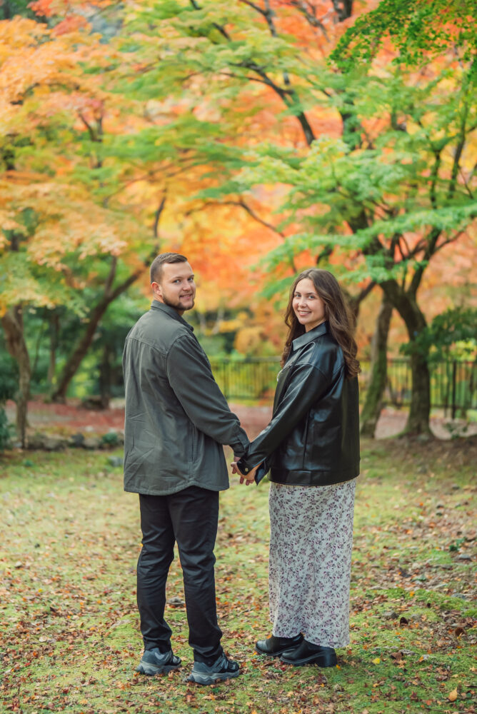 Romantic couple smiling together surrounded by beautiful autumn foliage in Arashiyama Kyoto