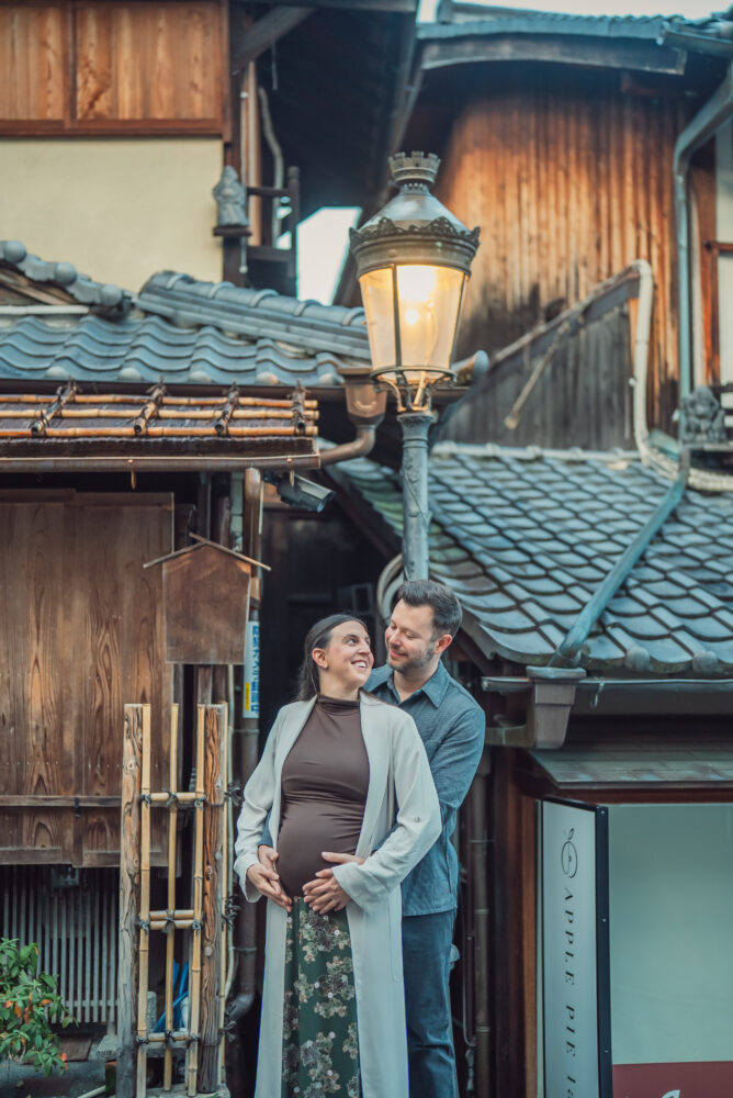 Expecting couple standing under a traditional street light on Ninenzaka in Higashiyama Kyoto during a maternity photoshoot