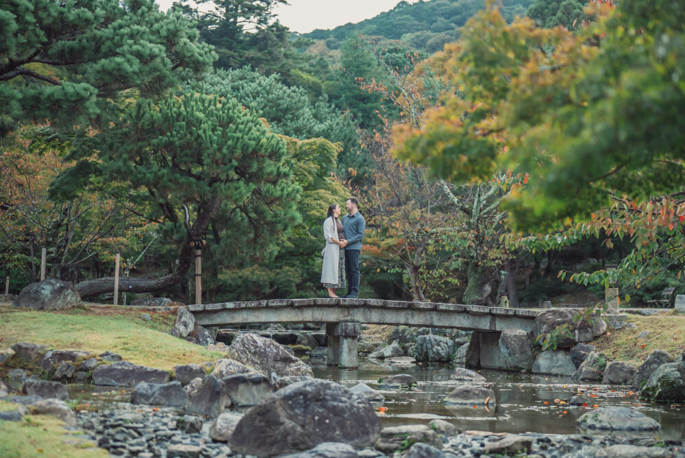 Expecting couple standing on a traditional bridge at Maruyama Park in Kyoto during a romantic maternity photoshoot