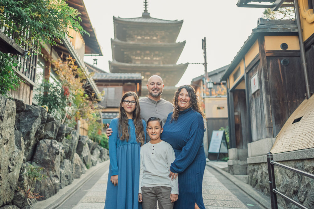 A family sharing a warm hug with Yasaka Pagoda in the background, illuminated by the soft morning light during a Kyoto family photoshoot