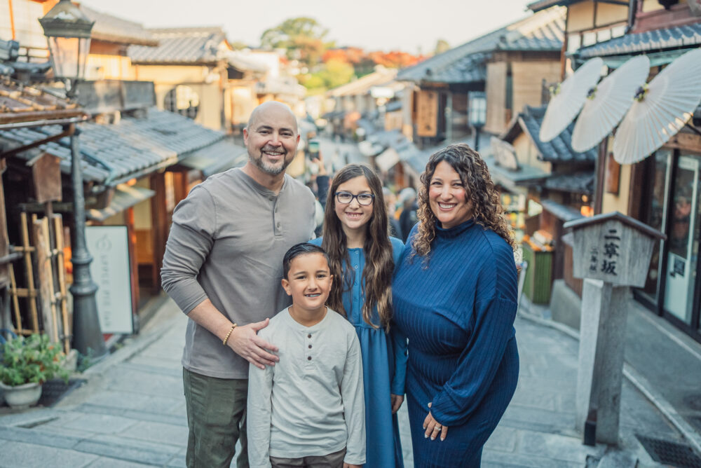 A happy family smiling together on the historic Ninen-zaka Street during a family photoshoot in Kyoto