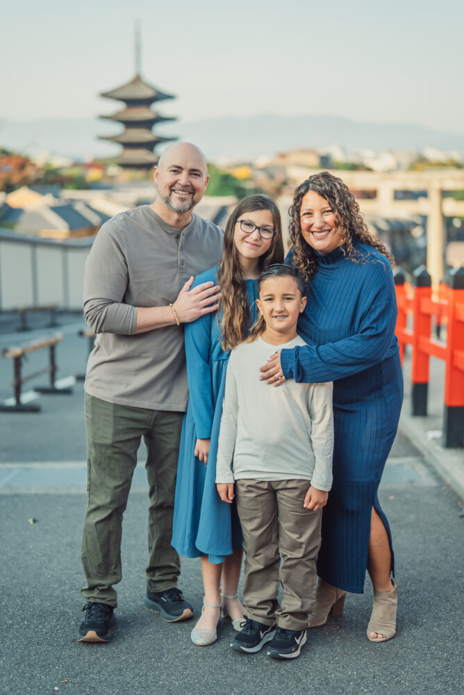 A family hugging on a hillside with Yasaka Pagoda in the background during a Kyoto family photoshoot