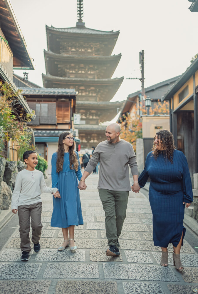 A family walking together with Yasaka Pagoda in the background, bathed in the soft morning light during a Kyoto family photoshoot
