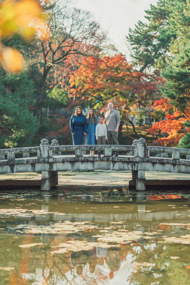 A family enjoying a beautiful moment surrounded by vibrant red maple leaves in Maruyama Park Kyoto