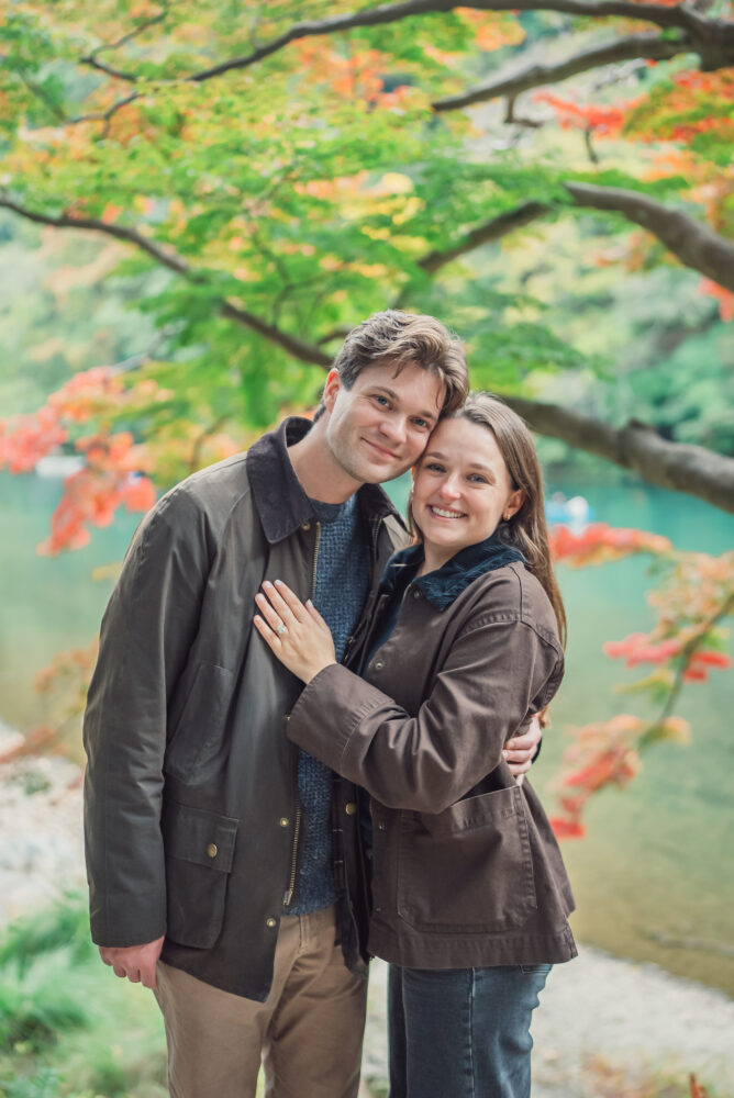 Couple sharing a romantic proposal moment with Hozu River and autumn foliage in Arashiyama Kyoto