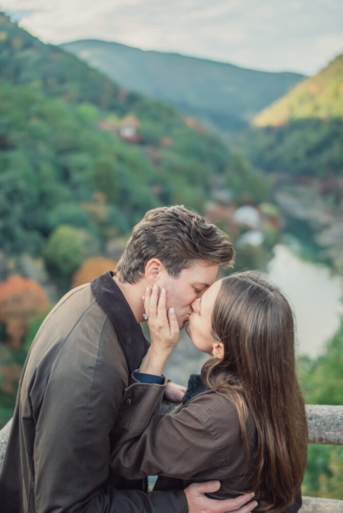 Couple sharing a romantic moment at a viewpoint overlooking Hozu River during a proposal photoshoot in Arashiyama Kyoto