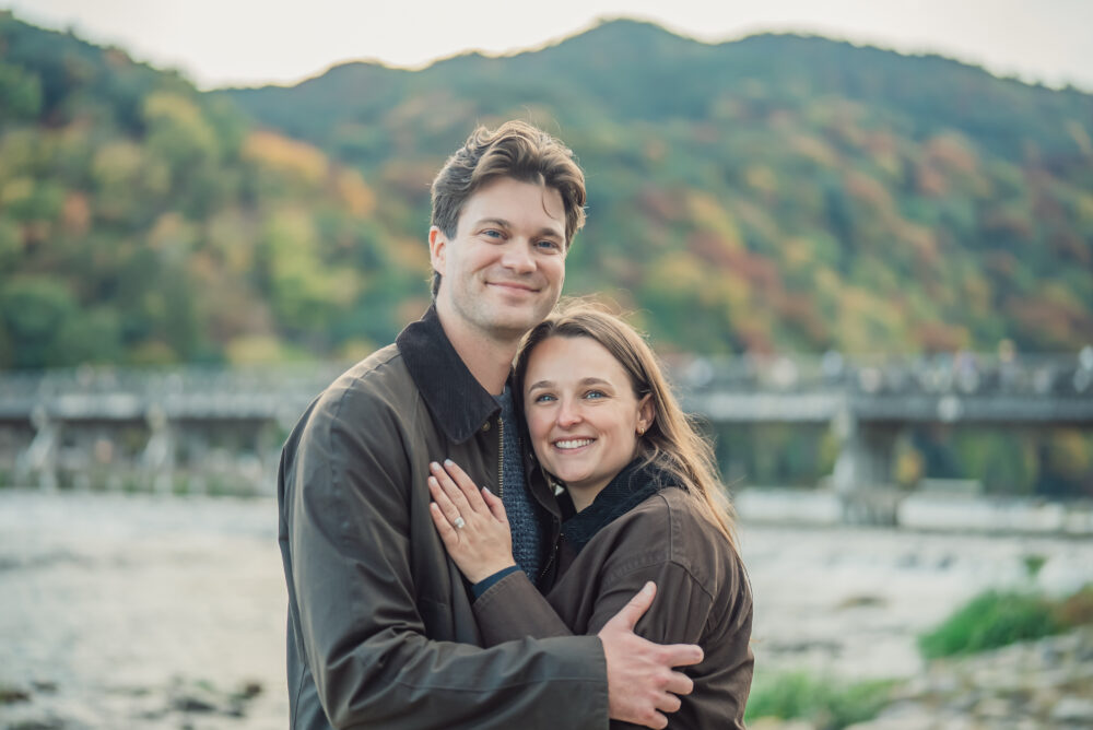 Romantic proposal moment between a couple with Togetsukyo Bridge and the beautiful Arashiyama landscape behind them
