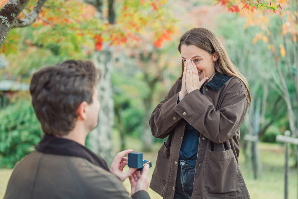 Proposal moment between a couple surrounded by vibrant autumn maple leaves in Arashiyama Kyoto Japan