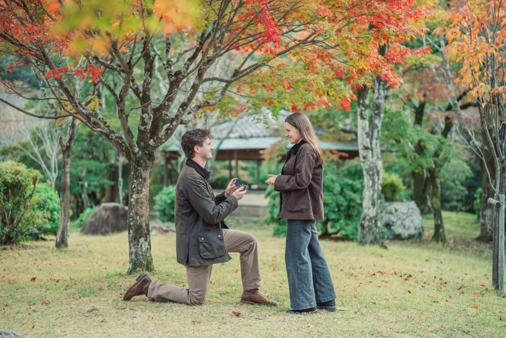 Couple celebrating a proposal surrounded by colorful autumn foliage and beautiful mountain scenery in Arashiyama Kyoto
