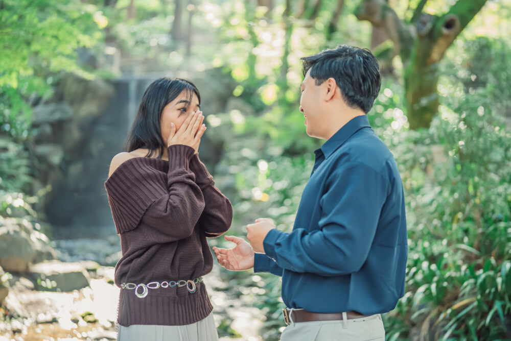 Romantic proposal moment at a waterfall in Maruyama Park Kyoto during an autumn couple photoshoot