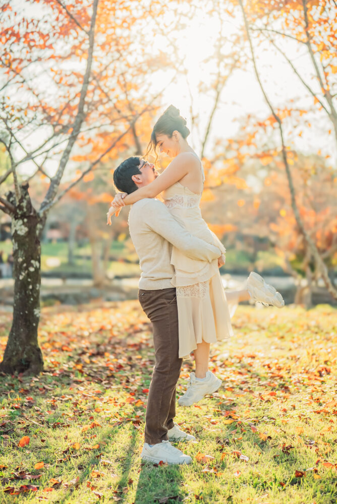 Engaged couple sharing a romantic moment in Kyoto surrounded by colorful autumn leaves and gentle sunset light