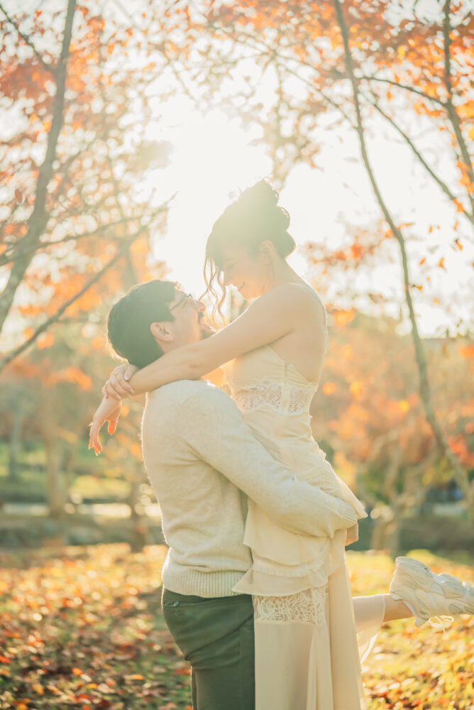 A romantic couple surrounded by autumn leaves and soft sunset light during a Kyoto photoshoot with a warm and peaceful atmosphere