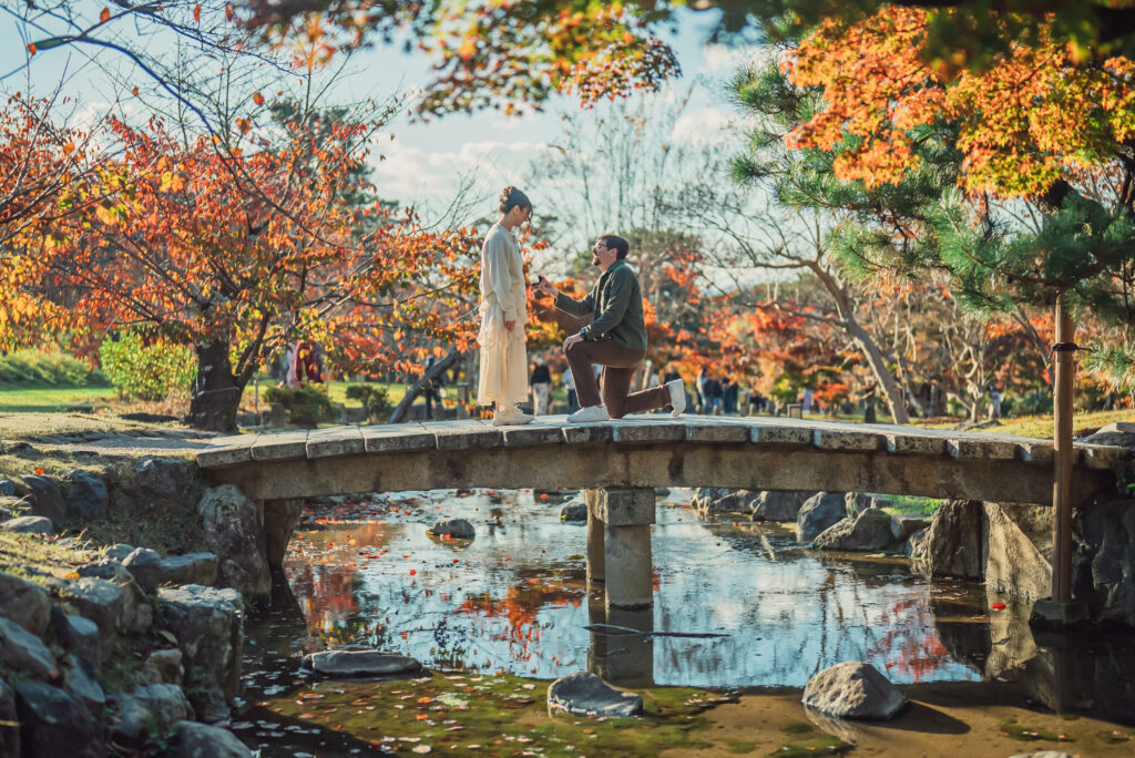 A romantic proposal at Maruyama Park bridge in Kyoto during sunset with beautiful autumn leaves surrounding the couple