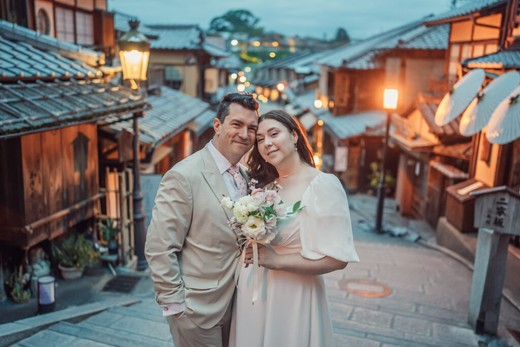 A couple standing on Ninen-zaka in Higashiyama Kyoto with traditional street lights during an early morning Kyoto elopement and pre wedding photoshoot.