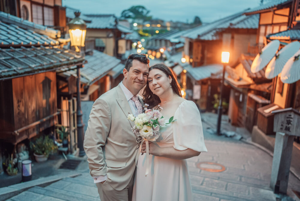 A couple standing on Ninen-zaka in Higashiyama Kyoto with traditional street lights during an early morning Kyoto elopement and pre wedding photoshoot.