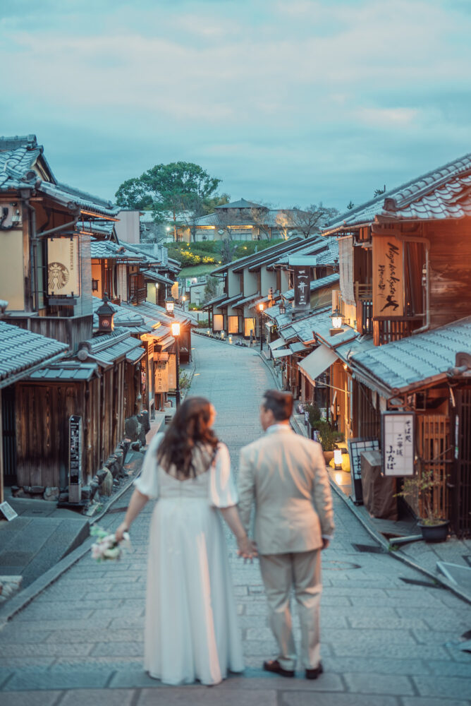 A romantic couple walking through lantern-lit Ninen-zaka in Higashiyama Kyoto during an early morning Kyoto elopement and pre wedding photoshoot.