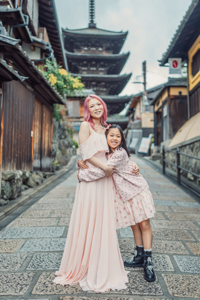 A mother and daughter hugging during a natural Kyoto family photoshoot with Yasaka Pagoda in the background in Higashiyama district
