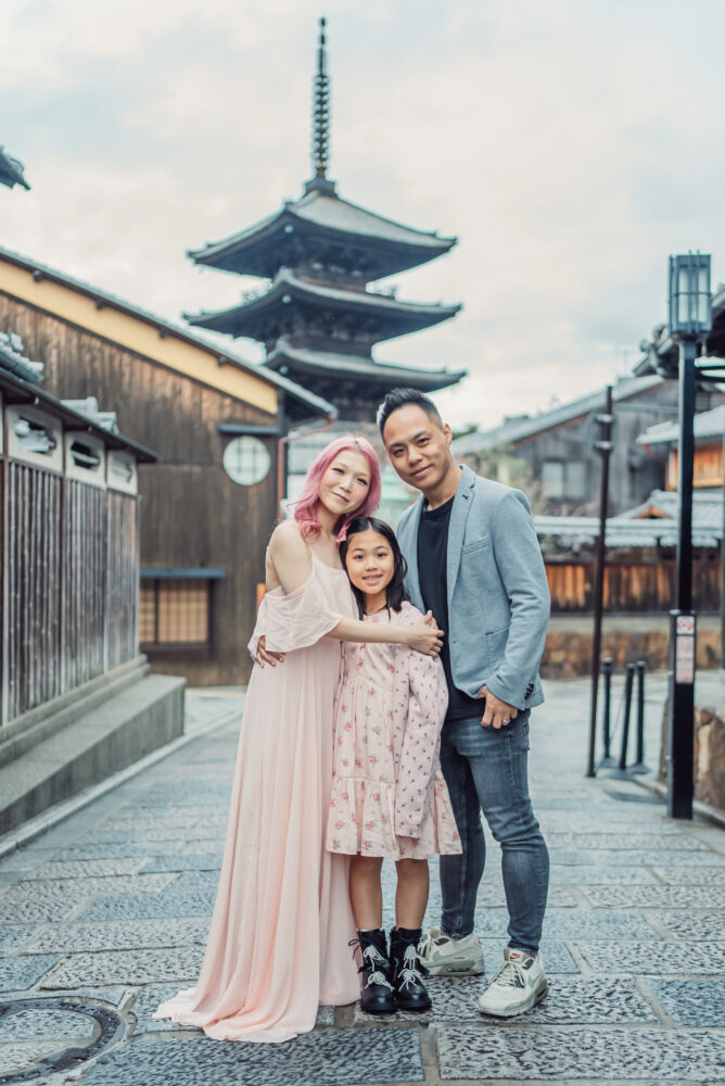 A family capturing memories of their Japan trip with Yasaka Pagoda and traditional Kyoto streets in the background