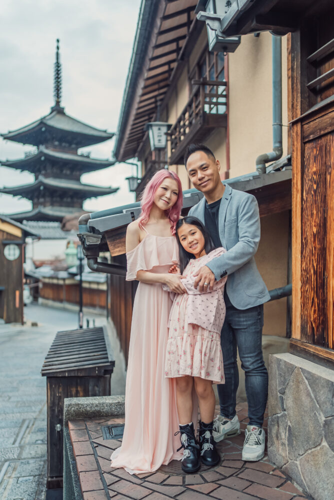 A happy family posing naturally with Yasaka Pagoda behind them during a Kyoto family photoshoot