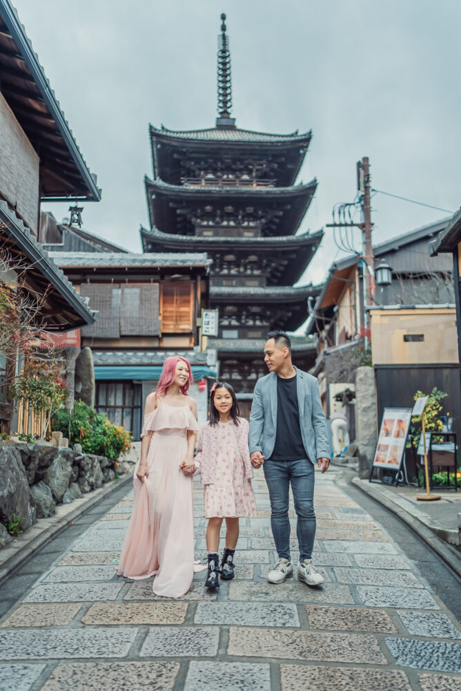 A family walking near Yasaka Pagoda while capturing natural moments during their Kyoto family photoshoot in spring