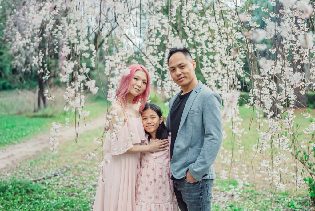 A happy family enjoying a natural Kyoto family photoshoot under cherry blossoms during their Japan trip