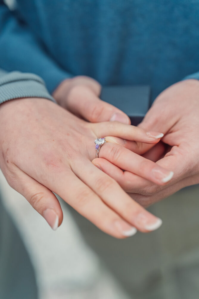 A close-up of an engagement ring on the bride-to-be's finger with soft cherry blossoms in the background at Philosopher's Path in Kyoto.