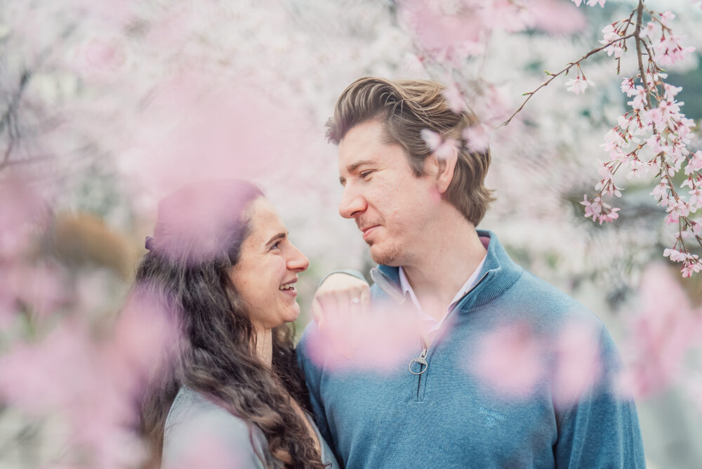 A couple standing together by a canal surrounded by blooming cherry blossoms on Philosopher’s Path in Kyoto
