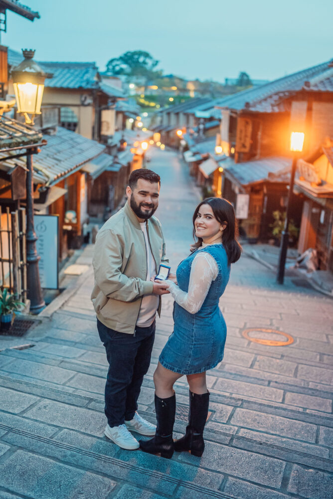 A romantic couple smiling in front of Ninen-zaka traditional streets during a Kyoto engagement photoshoot in Higashiyama.