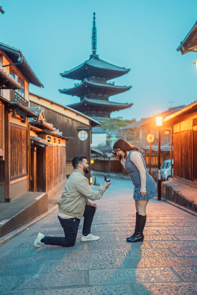 An engaged couple recreating a romantic proposal moment in front of Yasaka Pagoda during a Kyoto engagement photoshoot in Higashiyama.